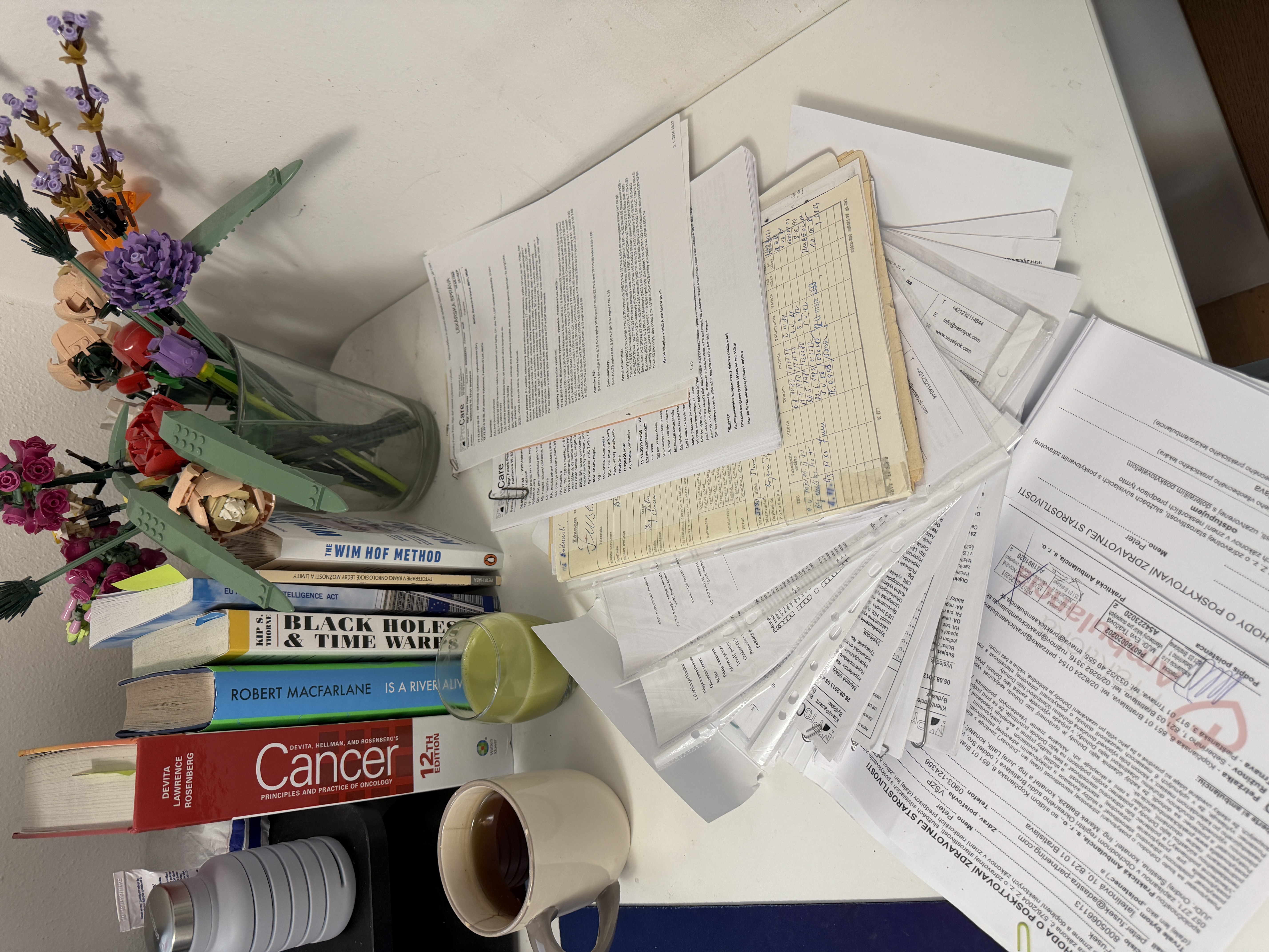Medical records spread across a desk — forty years of paper documents, lab results, and oncology textbook.